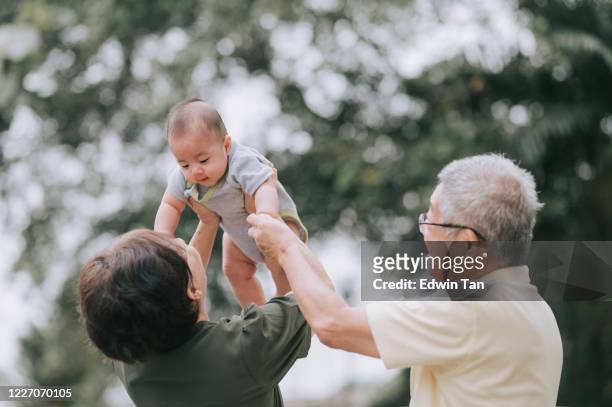 an asian chinese senior couple playing with their grandson at the front yard of their house - baby grandpa imagens e fotografias de stock
