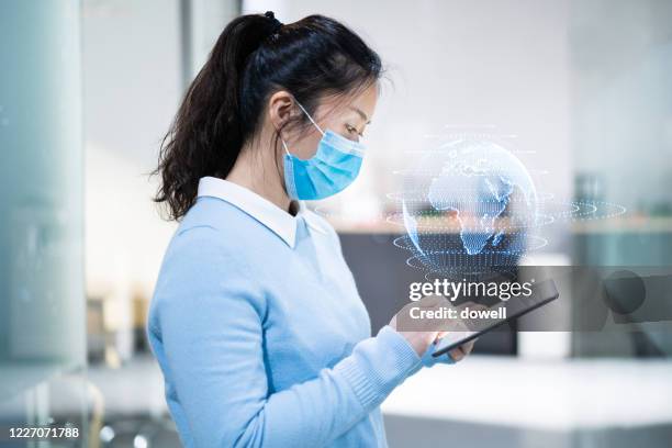 businesswoman with protective face mask uses mobile phone on virtual visual screen in office - big data therapie stock-fotos und bilder