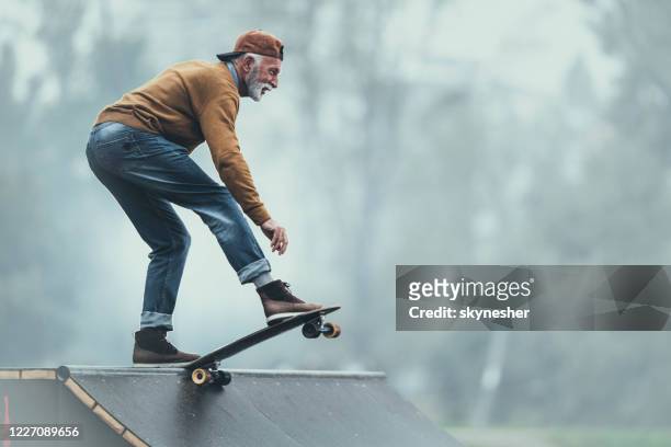 happy senior man skateboarding on a ramp at the park. - skating stock pictures, royalty-free photos & images