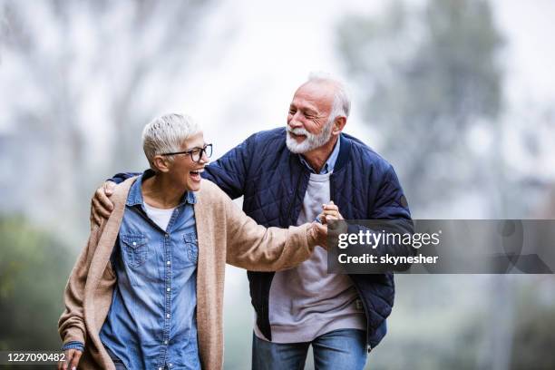cheerful senior couple having fun in the park. - mature couple winter outdoors stock pictures, royalty-free photos & images