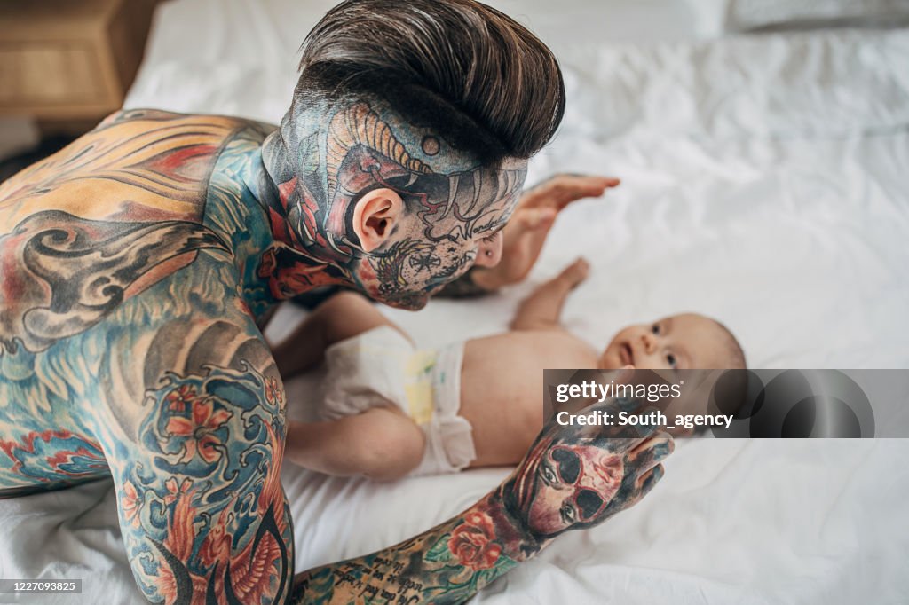 Modern Father With Whole Body Covered In Tattoos Lying With His Baby Son On  Bed In Bedroom High-Res Stock Photo - Getty Images