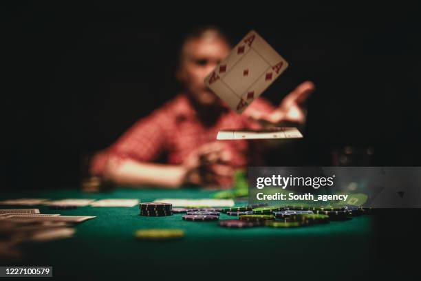 mature man throwing playing cards on table - casino interior stock pictures, royalty-free photos & images