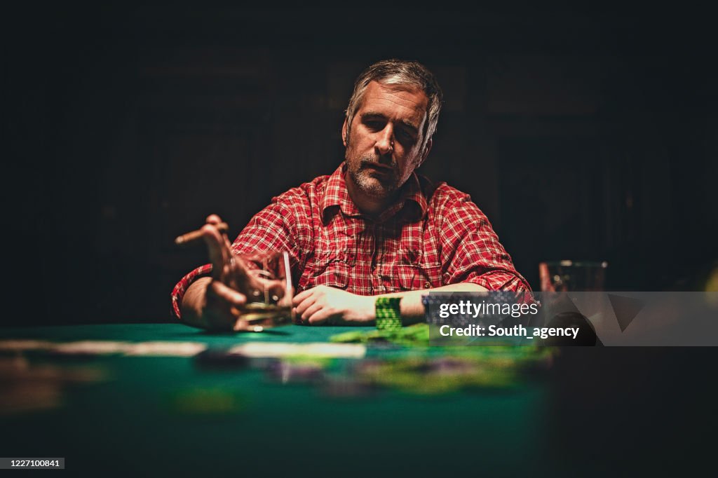 Mature man playing poker late by night