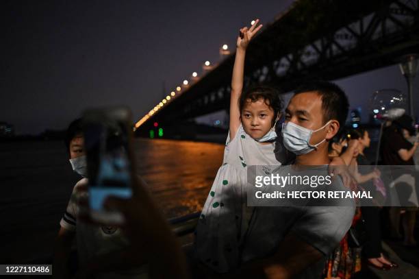 Residents wearing face masks are seen next to the Yangtze River in Wuhan in China's central Hubei province, on July 14, 2020. Various parts of China...
