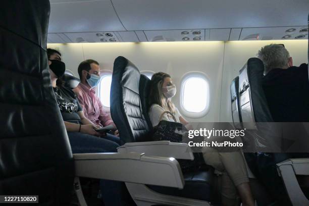 Female and male passengers wearing facemasks during the flight. Flying in an Olympic Air De Havilland Canada DHC-8-400 Turboprop aircraft during the...