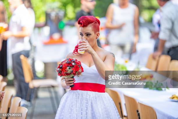 mariage d’été avec la mariée rousse dans la robe blanche tenant des fleurs et buvant la bière fraîche - photo stock - rockabilly stock photos et images de collection