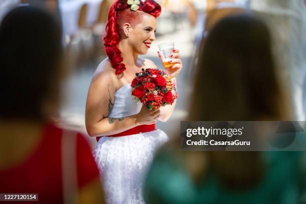 sposa in attesa di sposarsi tenendo fiori rossi e bevendo birra - foto di repertorio - rockabilly foto e immagini stock