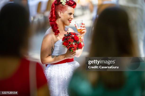 bride waiting to get married holding red flowers and drinking beer - stock photo - rockabilly stock pictures, royalty-free photos & images