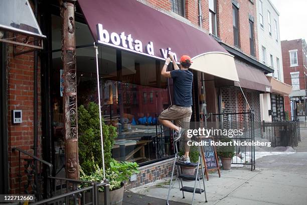 Local resident of Red Hook and wine shop owner, Jeff Botta, fixes his shop's sign, Botta Di Vino, August 28, 2011 in the Brooklyn borough of New York...