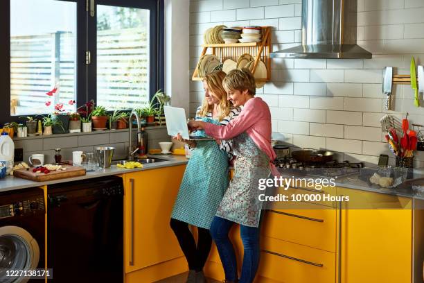 same sex couple using laptop together in kitchen - couple searching the internet stock pictures, royalty-free photos & images