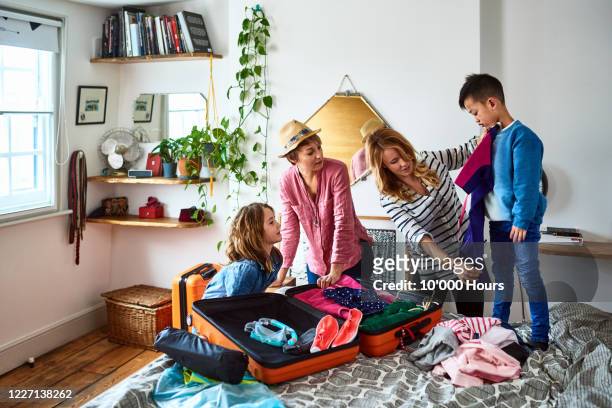 lesbian couple packing suitcases for holiday with children - pak stockfoto's en -beelden