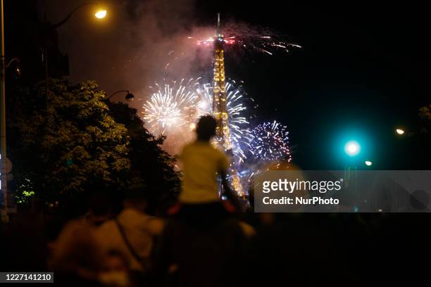 Boy watching the fireworks explode above the Eiffel Tower as part of the annual Bastille Day celebrations in Paris on July 14, 2020. France is...