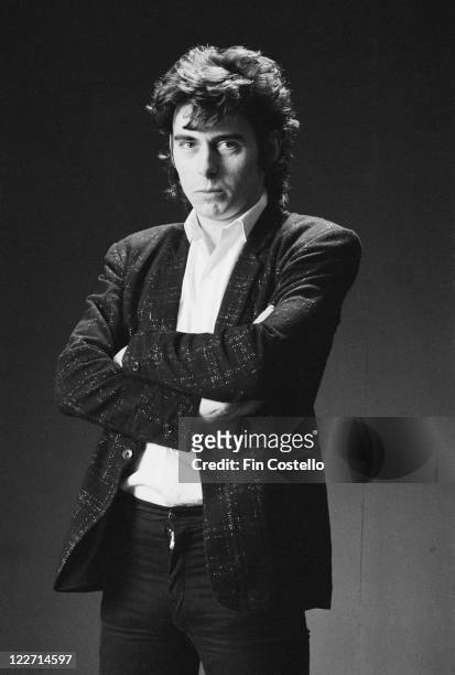 Pete Farndon , bassist with British rock band, The Pretenders, wearing a black jacket and a white shirt, with his arms folded, as he poses for a...