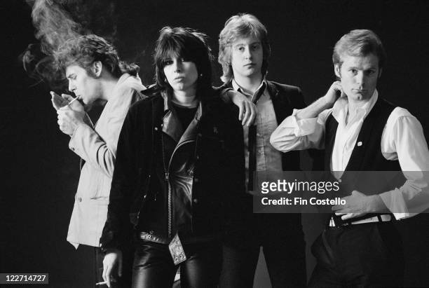 The Pretenders , British rock band, pose for a group studio portrait, against a black background, United Kingdom, in January 1979. Farndon is seen...