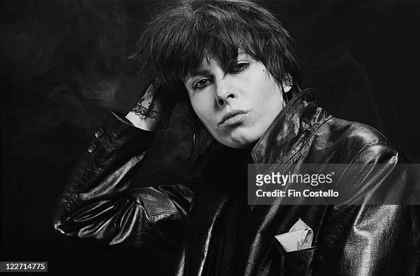 Chrissie Hynde, US singer and guitarist with rock band The Pretenders, wearing a black leather jacket in a studio portrait, against a black...