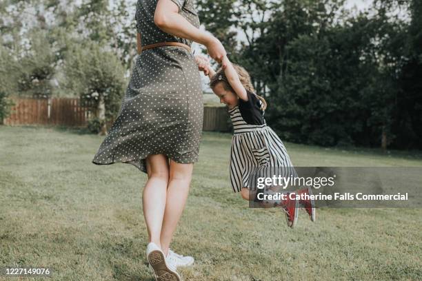 mother and daughter spinning - mom and young daughter stock pictures, royalty-free photos & images