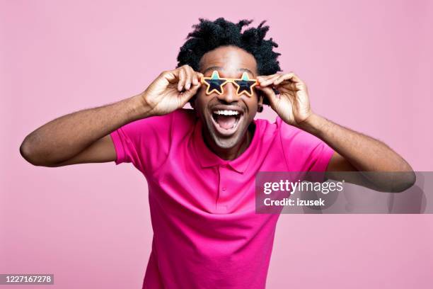 summer portrait of excited young man wearing star shaped sunglasses - sunglasses stock pictures, royalty-free photos & images