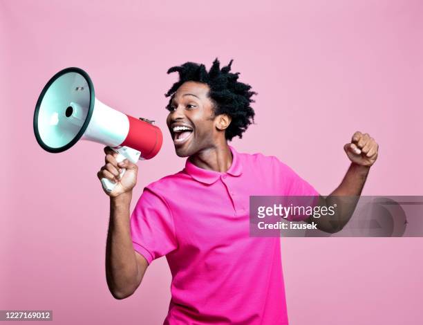 pink portrait of excited young man with megaphone - megaphone stock pictures, royalty-free photos & images