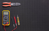 Multimeter, indicator screwdriver and wire stripper on a black rubber mat