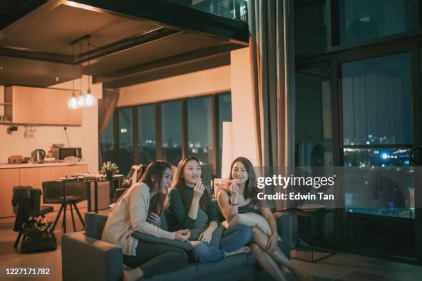 3 asiatische chinesische frauen mit freitagabend versammlung in der wohnung mit tv-film-nacht genießen snack sitzen auf dem sofa genießen jede firma - asian watching movie stock-fotos und bilder