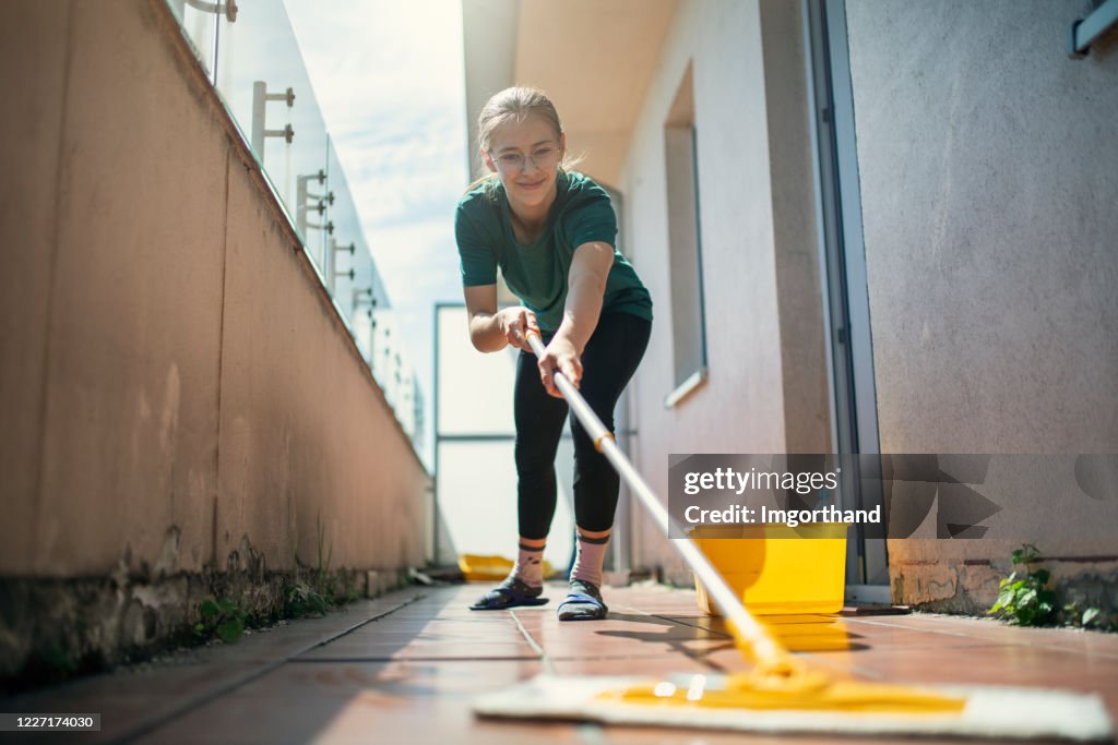 Teenage girl cleaning balcony