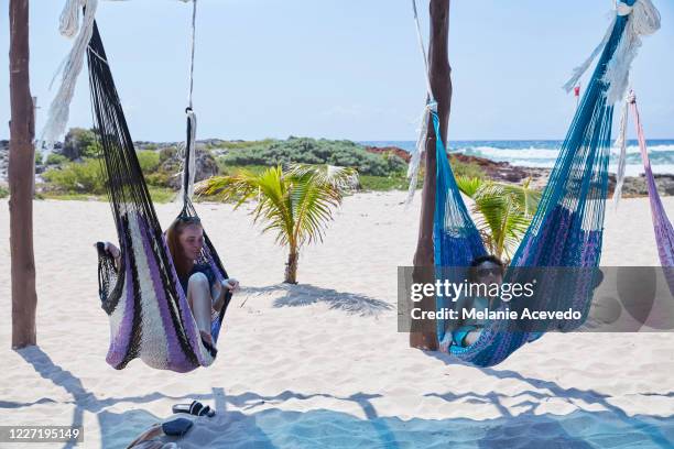 teenage sister and brother playing in hammocks on the beach in mexico. girl in one hammock and the bot in the other. they are messing around and having fun. - sandy messing stock pictures, royalty-free photos & images