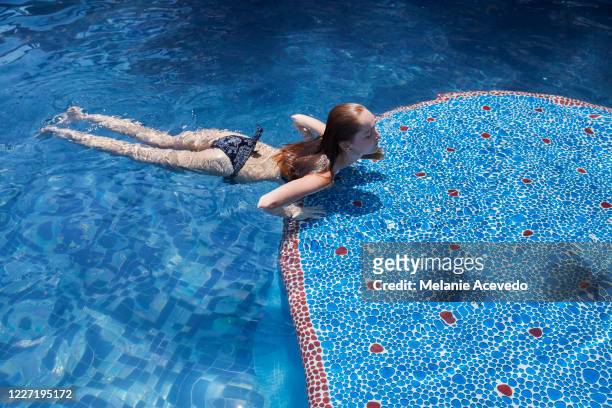 teenage girl swimming in a blue swimming pool in mexico. she is alone in the pool. - hot mexican girls stock-fotos und bilder