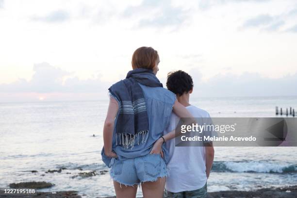 teenage sister and brother standing together watching the sunset  over the water in cozumel, mexico. their backs are to the camera. - hot mexican girls stock-fotos und bilder