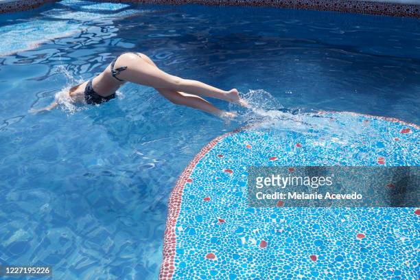 teenage girl diving into a blue swimming pool in mexico. she is alone in the pool. - hot mexican girls stock-fotos und bilder