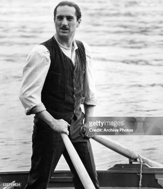 Robert De Niro standing in a boat holding oars in a scene from the film 'The Godfather: Part II', 1974.