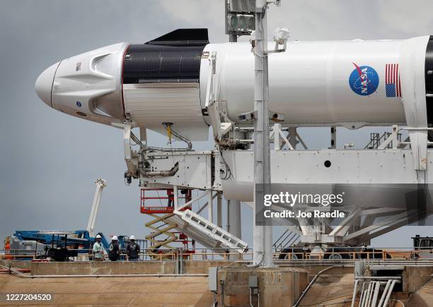 Workers prepare the SpaceX Falcon 9 rocket with the Crew Dragon spacecraft attached for tomorrow's scheduled liftoff from launch pad 39A at the...