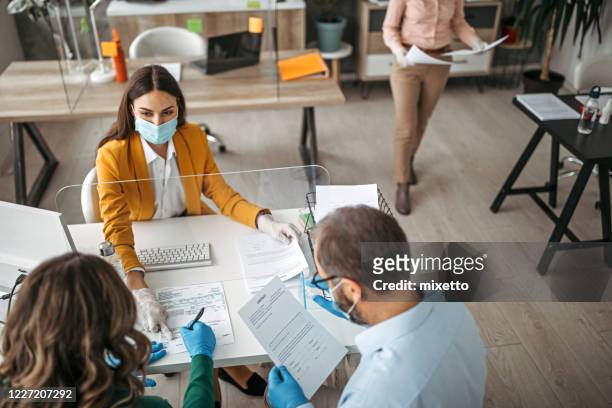 couple signing contract on meeting with insurance agent - bank office clerks stock pictures, royalty-free photos & images