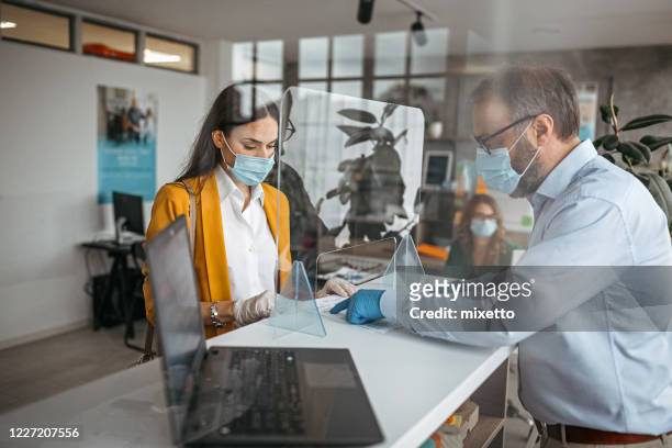 bank teller talking with customer at counter - protective face mask office stock pictures, royalty-free photos & images