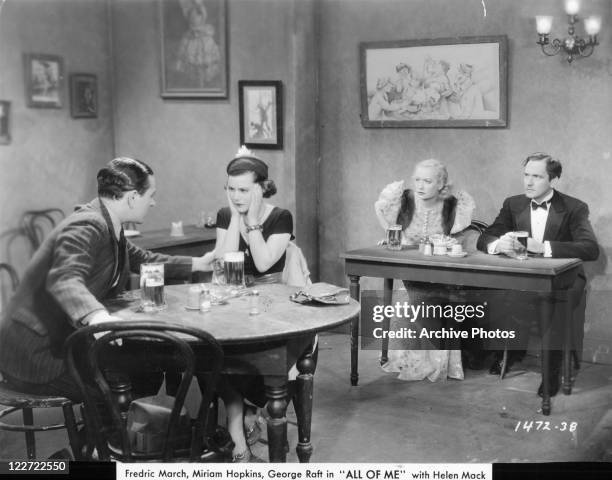 George Raft and Helen Mack sitting at a separate table than Miriam Hopkins and Fredric March in a scene from the film 'All Of Me', 1934.