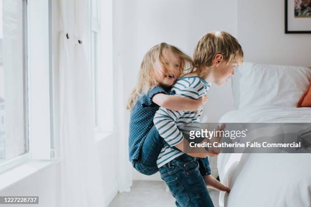 brother and sister in bedroom - family hugging bright stockfoto's en -beelden