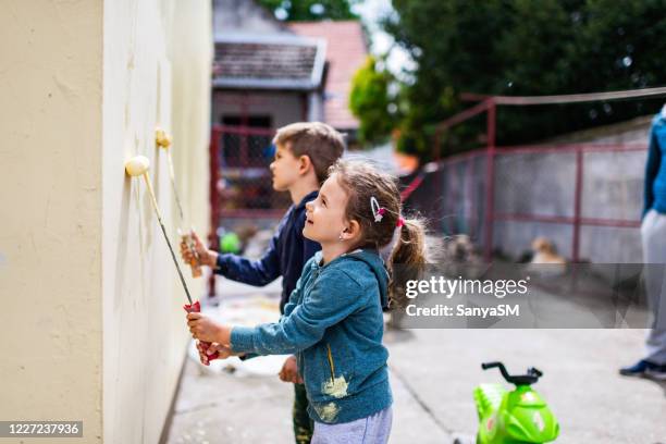 children helping painting the wall - paint roller stock pictures, royalty-free photos & images