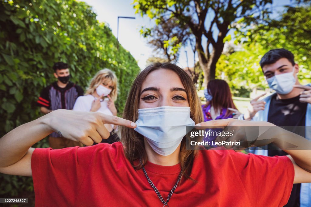 Group of teenagers posing showing their protective face masks