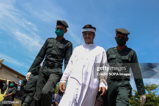 Islamic sharia officers escort a man wearing a face shield to be flogged in the open for violating Islamic Sharia law in North Aceh District. Islamic...