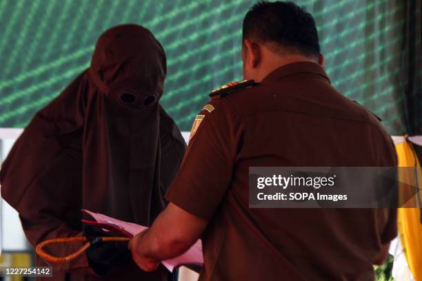 An officer hands over rattan to the executioner as a whip punishment tool for those that violate Islamic Sharia law in North Aceh District. Islamic...