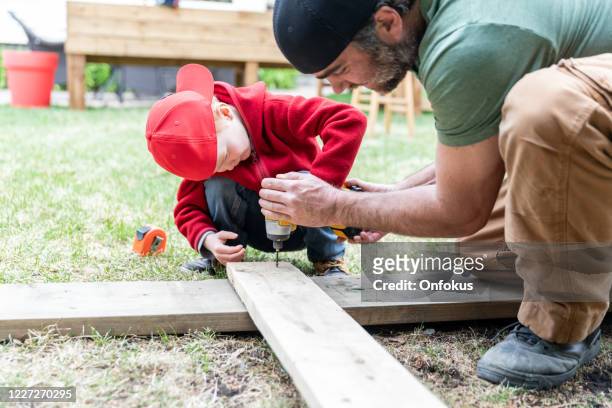 père et fils faisant un projet de construction tandis qu’en quarantaine - family garden play area photos et images de collection