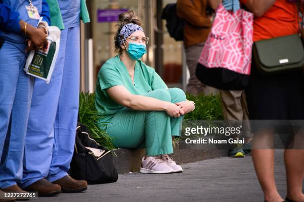Medical worker wears a protective face mask outside NYU Langone Health hospital as people applaud to show their gratitude to medical staff and...