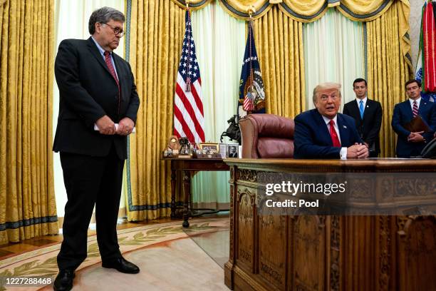 Attorney General William Barr listens as President Donald Trump addresses reporters in the Oval Office of the White House after receiving a briefing...