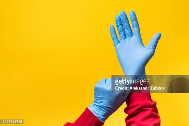 the woman puts on protective medical gloves. - surgical glove stock pictures, royalty-free photos & images