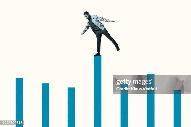 confident young man on top of blue bar graph - actuación conceptos fotografías e imágenes de stock