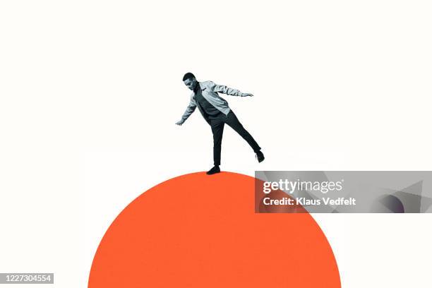 confident man balancing on orange semi-circle - social inequality photos et images de collection