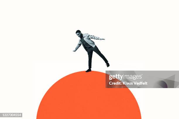 confident man balancing on orange semi-circle - vulnerability stock pictures, royalty-free photos & images