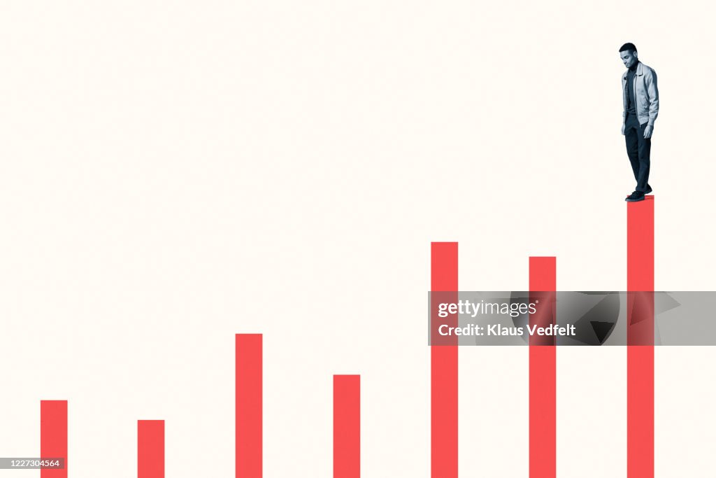 Young man standing on top of coral bar graph