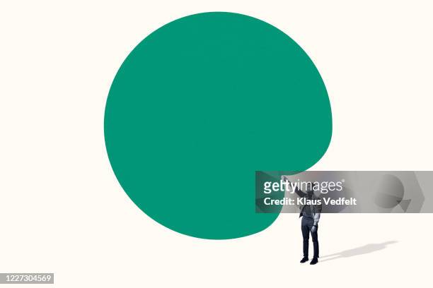 confident young man poking large green blob - grüner mantel stock-fotos und bilder