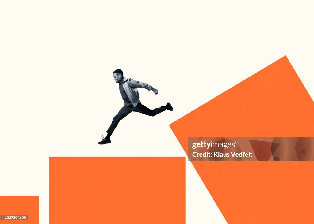 Happy young man running on large orange bar graph