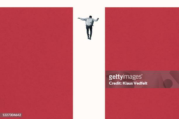 rear view of young man falling between red columns - bias stock-fotos und bilder